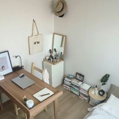 a bedroom with a bed, desk and mirror in it's corner next to a wall mounted clock