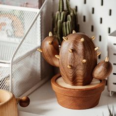 a wooden cactus sitting on top of a table next to a pot filled with cacti