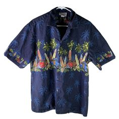 a blue hawaiian shirt with surfboards and palm trees on the chest, in front of a white background