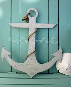 an anchor on the side of a blue wooden wall next to a white fish statue