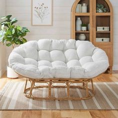 a white couch sitting on top of a wooden floor next to a book shelf and potted plant