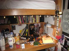 a bed room with a wooden desk and bookshelf full of stuff on it