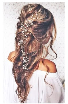 the back of a woman's head with long hair and flowers in her hair