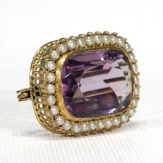 This mid to late Victorian brooch was lovingly handcrafted in 9 karat gold and is set with a stunning, deep purple rectangular cushion cut amethyst. Bezel set, with a fine millegrain border this jubbly gem measures 21.8 x 14 x 7.1 mm, and has estimated carat weight of an impressive 12.6 carats. Sitting atop a fine, hand pierced gallery, it is surrounded by a single row of thirty fine natural pearls. This exquisite jewel was most likely made between 1870 and 1880, and though unmarked it has been Thirty Fine, Hand Piercing, Victorian Brooch, Rectangular Cushion, Memorial Ring, Sapphire Band, Pearl Brooch, Antique Jewellery, Natural Pearls