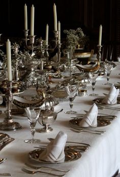 a long table is set with silverware and candles