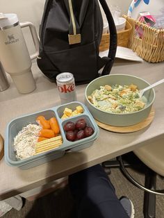 two trays of food sitting on a table with a backpack in the back ground