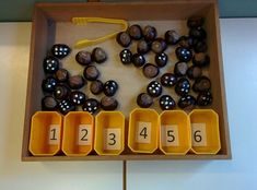 a wooden box filled with lots of black and white balls next to numbers on yellow tray