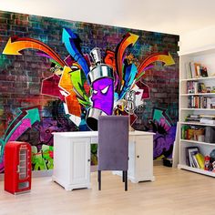 a colorful mural on the side of a brick wall next to a desk and chair