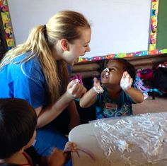 a woman and two children sitting at a table with frosting on their hands in front of a cake