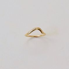 a yellow gold ring with diamonds on it, sitting on a white surface in front of a plain background