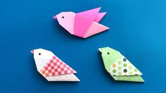 three origami birds sitting next to each other on a blue surface with polka dots