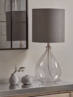 a lamp that is sitting on a table next to a vase with flowers in it