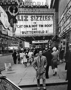 an old black and white photo of people walking in front of a movie theater with the marquee lit up