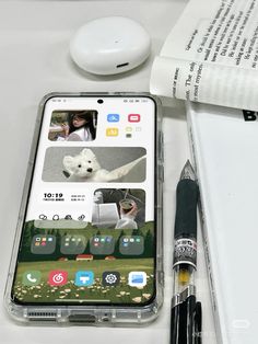 a cell phone sitting on top of a white table next to a pen and paper