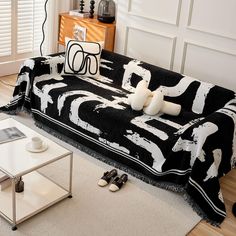 a black and white couch sitting on top of a wooden floor next to a coffee table