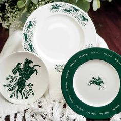 three green and white plates sitting next to each other on a tablecloth with flowers in the background