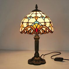 a stained glass lamp on a table with a cord plugged into the light bulb