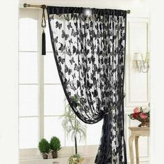 black butterfly print sheer curtain hanging from the side of a window in a living room