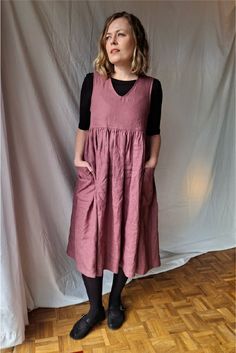 a woman standing in front of a white backdrop wearing a pink dress and black socks