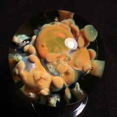 an orange and black glass object with bubbles on it's side, sitting on a table