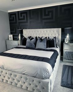 a large bed with black and white pillows on it's headboard in a bedroom