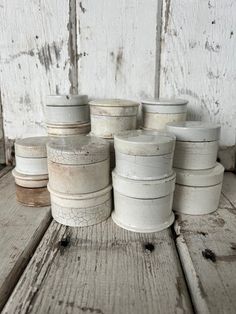 several white pots are stacked on top of each other in front of a wooden wall