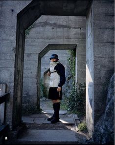 a man standing in an archway with a hat on his head and wearing a kilt