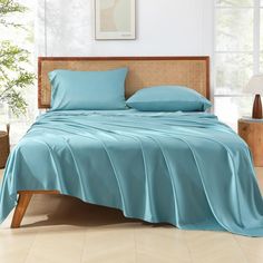 a bed with blue sheets and pillows in a room