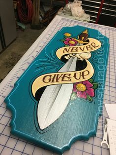 a surfboard with a banner on it sitting on top of a cutting board that says never give up