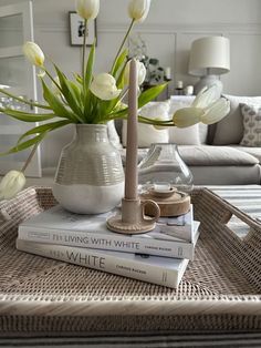 a table topped with books and vases filled with white flowers on top of each other