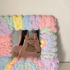 a woman taking a selfie in front of a multicolored cake