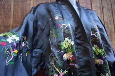 "Vintage charcoal/black floral embroidered robe. Open front.  No waist tie. Good vintage condition! condition - see photos ✂Measurements✂ shoulders: 24\" length: 54\"" Spring Embroidered Long Robe, Spring Long Embroidered Robe, Black Fitted Long Kimono, Fitted Black Robe With Long Sleeves, Fitted Long Black Kimono, Vintage Black Kimono For Spring, Black Embroidered Long Sleeve Kimono, Black Kimono With Floral Embroidery, Fitted Black Traditional Kimono