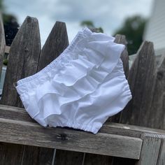 a white diaper sitting on top of a wooden fence