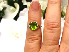 This sweet Art Deco ring has an oval cut green stone, tested on a Presidium gem tester as glass. The pretty stone measures approximately 9mm x 7mm or 1.86 carats, has minimal surface wear consistent with age and is set with four yellow gold prongs with decorative scroll filigree on the side gallery. This lovely stone, most likely meant to imitate peridot, is a pretty contrast color to the 10K yellow gold setting measuring approximately 13mm x 9.5mm with a 5mm rise off the finger. The band measur August Birthstone Ring, Minimal Surface, Sweet Art, Mother Rings, Glass Ring, August Birthstone, Yellow Gold Setting, Deco Ring, Ring Oval