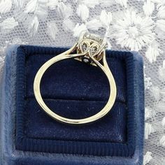 a diamond ring sitting on top of a blue velvet box