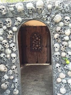 there are many skulls on the wall and in the entrance to this building that is made out of rocks