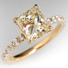 a yellow gold ring with a princess cut diamond in the center and pave set diamonds surrounding it