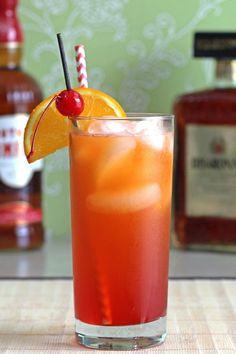 an orange drink with a cherry garnish on the rim and a striped straw