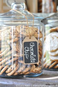 some cookies are in a glass jar with a tag hanging from the top, and another one has a chalkboard on it