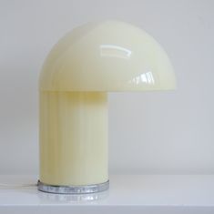 a white table lamp sitting on top of a white shelf next to a light bulb