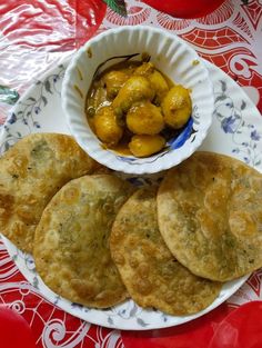 some food is sitting on a plate next to a bowl of pickles and sauce