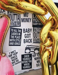 some gold and pink balloons in front of a wall with signs on it that read, to all the baby got back