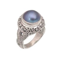 A cultured pearl tinted an iridescent blue seems to glow from the center of this magnificent cocktail ring. Bali's Putu Putri presents the ring which is crafted by hand of sterling silver. Beneath an ornately detailed crown silver bands of different patterns wind around one another.