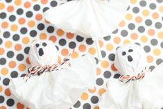 three halloween treats wrapped in white paper and tied with orange ribbon on polka dot background