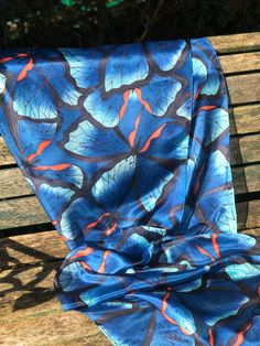 This beautiful, hand painted silk scarf is a wearable piece of art. Butterflies, in shade of blue with an orange accent, and outlined in black, have been hand painted onto the silk with specialist silk paint. The outline of the design is first drawn and then the colours are applied with brushes - the whole process takes many very enjoyable hours. The scarf has been professionally streamed in order to permanently fix the colours and preserve their vibrancy. This steaming process leaves the silk p Artistic Blue Silk Scarf For Spring, Hand Painted Blue Silk Scarf For Summer, Artistic Blue Silk Scarves, Blue Hand Painted Silk Scarf, Artistic Blue Silk Scarf, Artistic Handmade Blue Silk Scarf, Blue Bohemian Hand Painted Silk Scarf, Blue Hand Painted Bohemian Silk Scarf, Bohemian Blue Hand Painted Silk Scarf