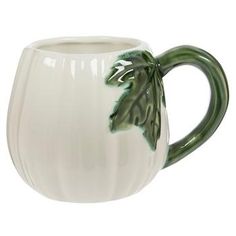 a white ceramic mug with green leaves on it