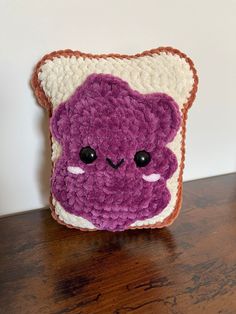 a purple and white crocheted bear on a table