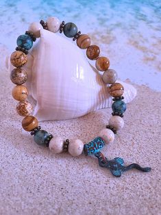 Get those sandy vibes flowing with our Beachy Bracelets, featuring natural stones, patina green accents, pearls, and cute ocean-inspired charms. Our Mykonos Collection would not be complete without some versatile, easy-to-use stretch bracelets. Wear one alone or stack a few for a bold BoHo look. Each bracelet features antiqued patina charms and spacers made in Greece, where the art of metal finishing was popular already thousands of years ago. Pearls, stingrays, shells, and other fun shapes ador Turquoise Jewelry With 8mm Beads For The Beach, 8mm Bead Bracelet For Beach, Brown Beaded Bracelets With Natural Stones For Beach, Brown Natural Stones Beaded Bracelets For Beach, Brown Natural Stone Beaded Bracelets For Beach, Handmade Bohemian Sand-colored Jewelry, Bohemian Gemstone Beads Bracelets For Beach, Bohemian Gemstone Beads Bracelet For Beach, Casual Beach Jewelry With 8mm Beads