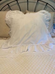 a bed with white sheets and pillows on it's headboard is shown in this image