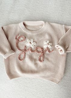 a knitted sweater with the word hope written in crochet, on a white surface